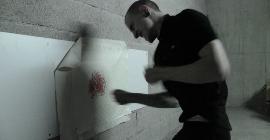 Французский художник Mac Blondie пробивает кулаками холст, повешенный на стену